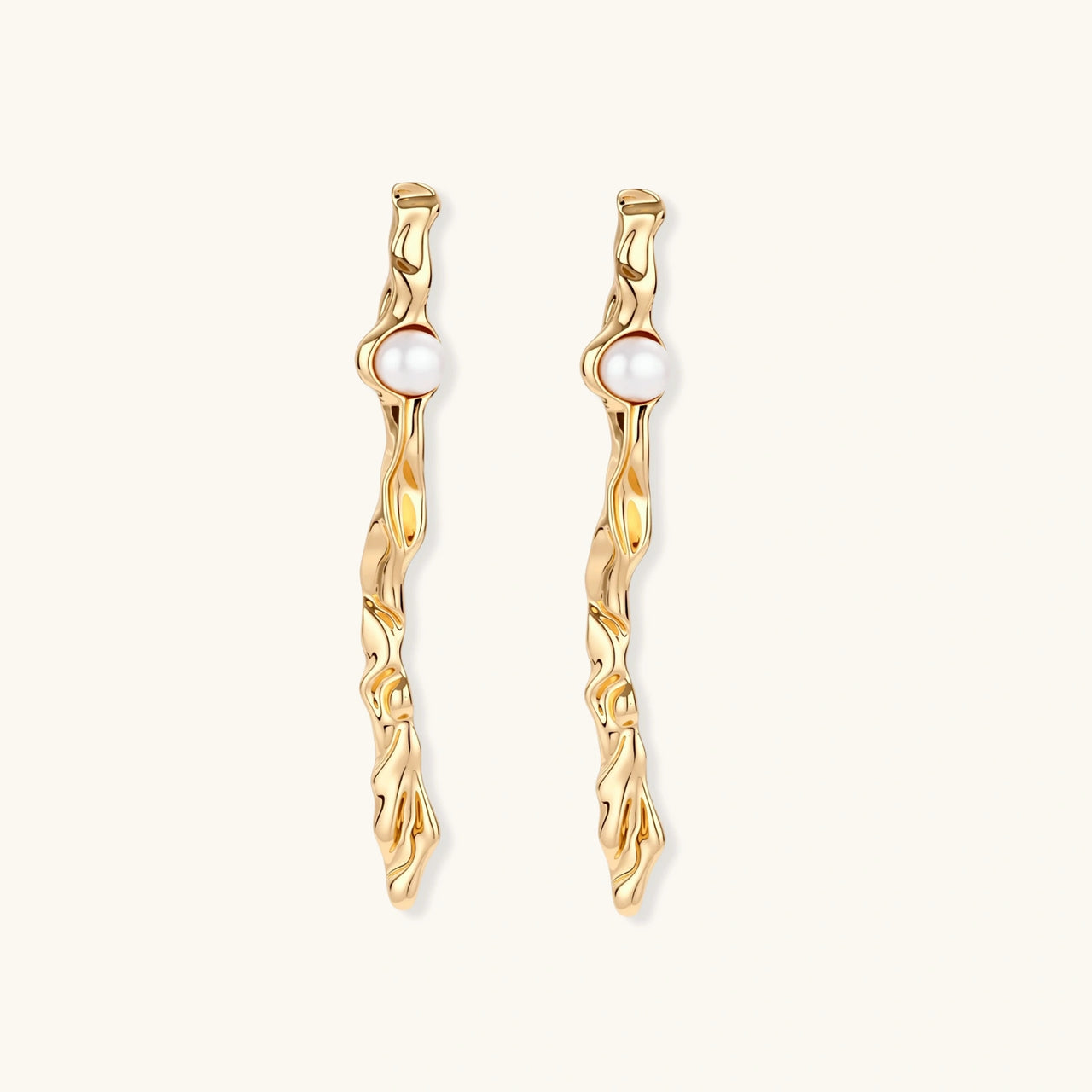 Organic twisted gold-toned drop earrings with white ABS pearls positioned near the top on cream background.